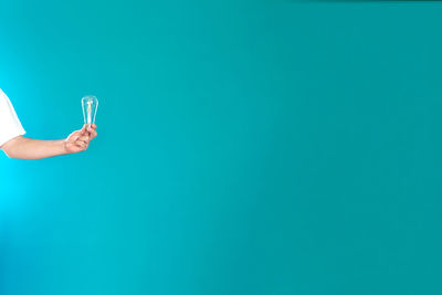 Midsection of woman holding ice cream against blue background