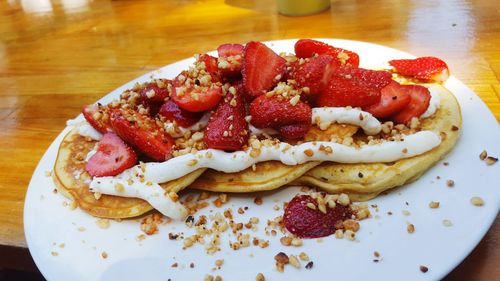 Close-up of pancakes with strawberries in plate on table