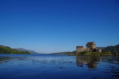 Buildings at waterfront against blue sky