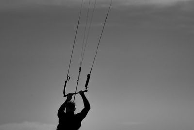 Rear view of silhouette man paragliding against sky