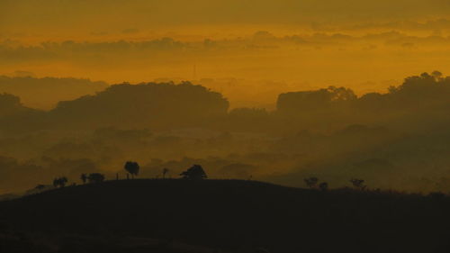 Silhouette landscape against sky during sunset