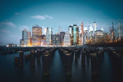 Reflection of illuminated buildings in river against sky