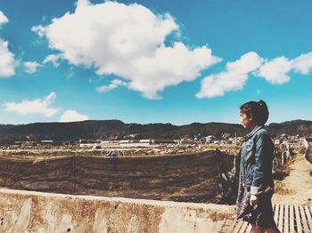 Side view of man standing on landscape against sky