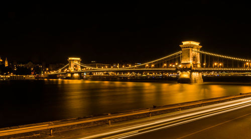 Illuminated suspension bridge over river at night