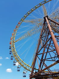 Low angle view of ferris wheel against blue sky