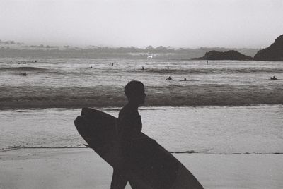 Rear view of man at beach against sky