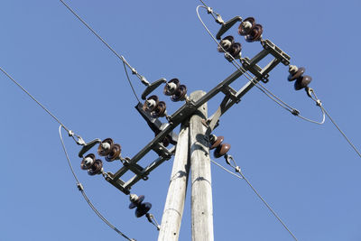 Low angle view of power lines against clear blue sky