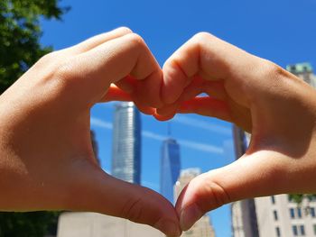 Close-up of hand holding hands against sky