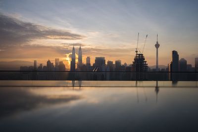 Petronas towers amidst buildings against sky during sunrise in city