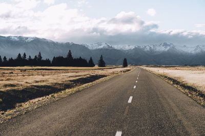 Road by mountains against sky