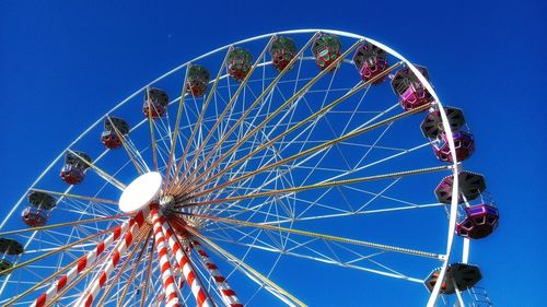 Low angle view of ferris wheel against clear blue sky