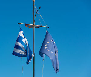 Greece flag and europe flag against a blue sky