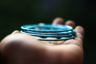 Close-up of hand holding bangles against black background