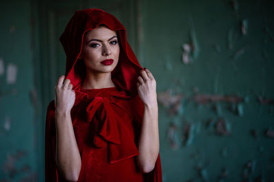 Portrait of beautiful young woman standing against wall