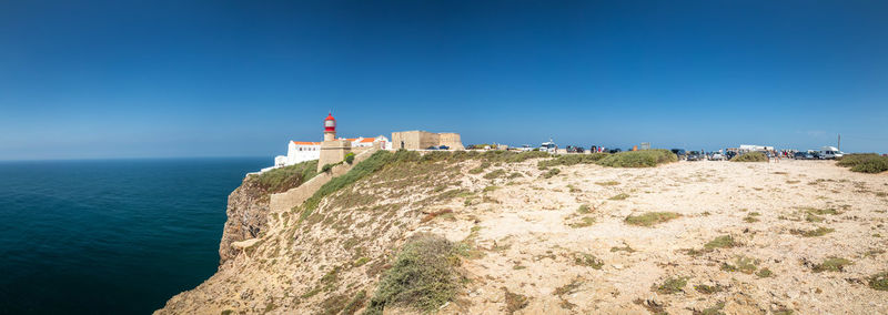 Lighthouse amidst sea and buildings against sky