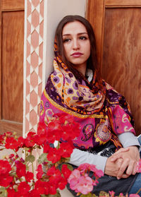 Portrait of beautiful young woman sitting against wall