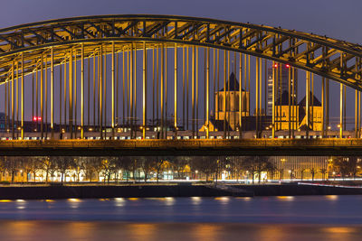 Illuminated bridge over river at night