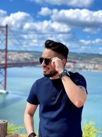  man wearing sunglasses standing by sea against sky