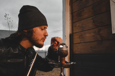 Side view of young man drinking glass