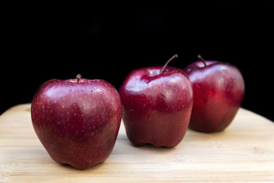 Close-up of wet apple on table against black background
