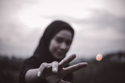 Portrait of human hand against sky