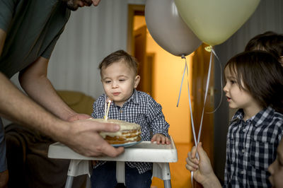 Father with birthday cake celebrating son's birthday at home