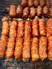 Preparing meat rolls called mici or mititei on
barbecue. 