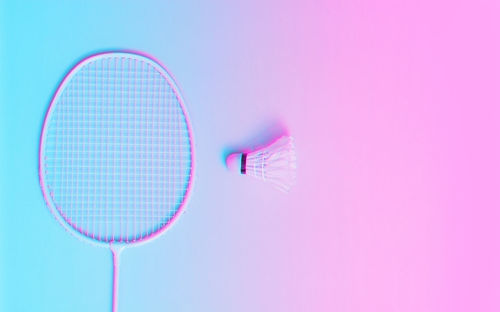 Close-up of badminton racket with shuttle cock pink and blue background