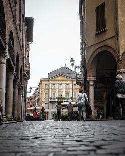 People on street amidst buildings in city against sky