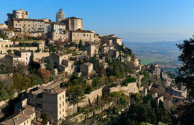 High angle view of houses on cliff at gordes against blue sky