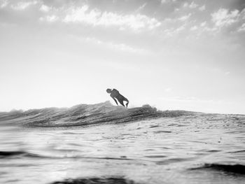 Silhouette man diving in sea against sky