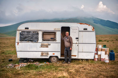 Man standing with travel trailer on mountain against sky