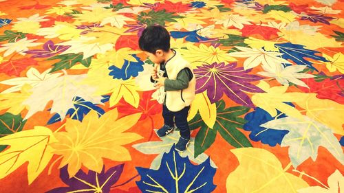 High angle view of boy standing in autumn leaves