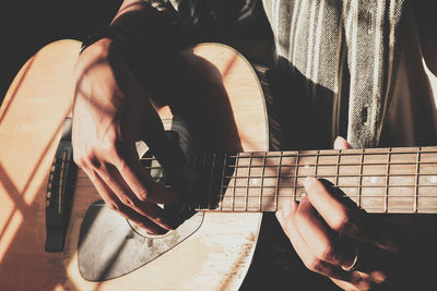 Midsection of man playing acoustic guitar