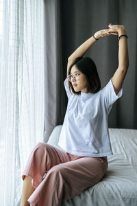 Young woman sitting on bed at home