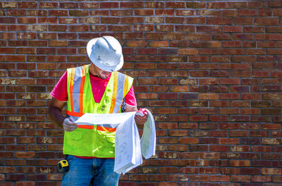 Rear view of man standing against brick wall