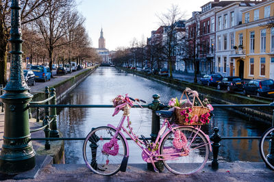 Bicycles on bridge over canal amidst buildings in city