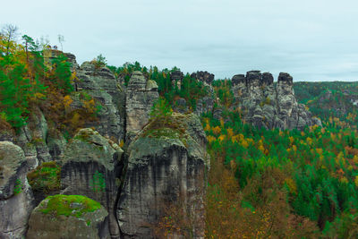 View of rock formations against sky with beautiful forest in autumn, saxon switzerland mountains