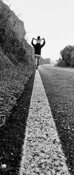 Rear view of woman on road against clear sky