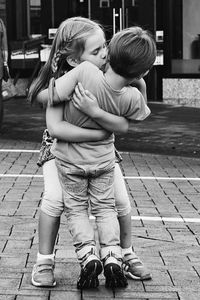 Cute brother and sister embracing on street