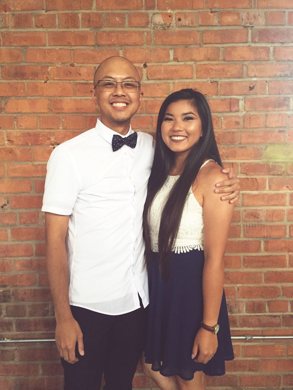 brick wall, young adult, young women, full length, casual clothing, person, standing, long hair, lifestyles, wall - building feature, couple - relationship, bonding, smiling, love, portrait, leisure activity, looking at camera, togetherness, confidence, front view, friendship, well-dressed, medium-length hair, black hair