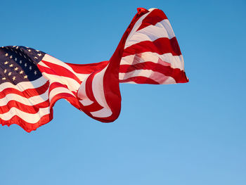 Low angle view of flag against clear blue sky