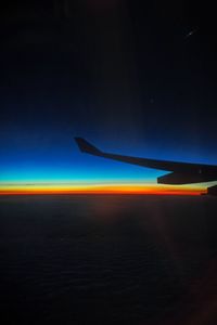 Airplane wing against sky during sunset