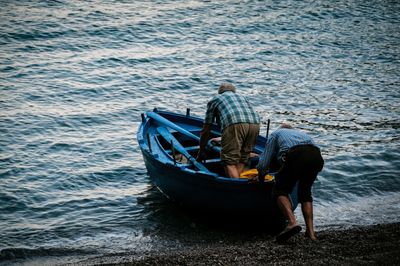 Rear view of man with boat in sea