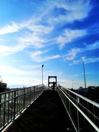 Man on bridge against blue sky