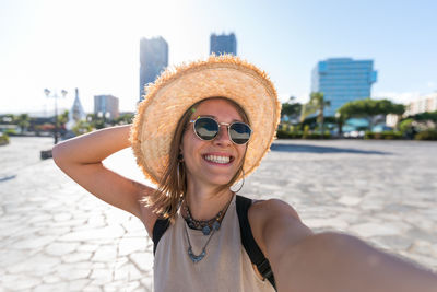 Portrait of smiling young woman wearing hat standing outdoors