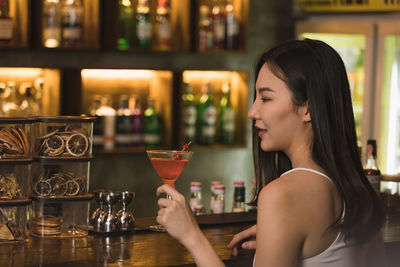 Side view of young woman holding wineglass