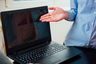 Midsection of man using laptop on table