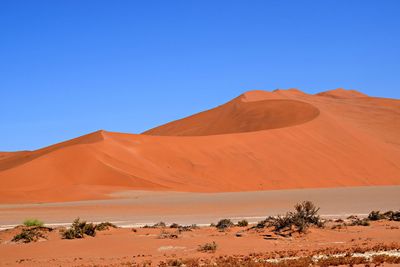 Scenic view of desert against clear blue sky