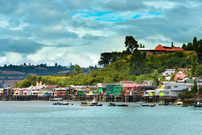 Houses by sea against sky